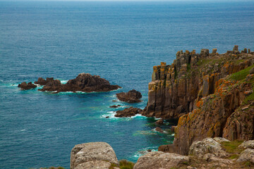 steep cliffs at the rugged Atlantic coast of Cornwall, UK. This landscape features unique rock formations with cracks and moss generating a delicate texture. Water is crystal clear but scary.