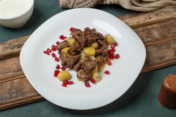 Meat sauteed with chestnuts and pomegranate seeds in a white plate