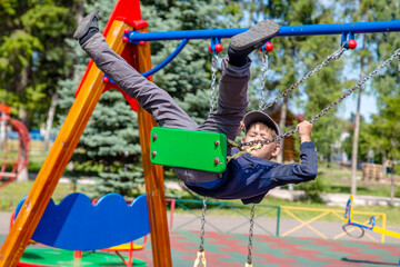 Fototapeta premium happy boy rides on a swing in the park