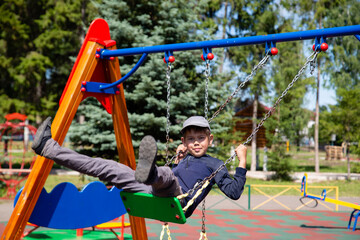 Fototapeta premium happy boy rides on a swing in the park