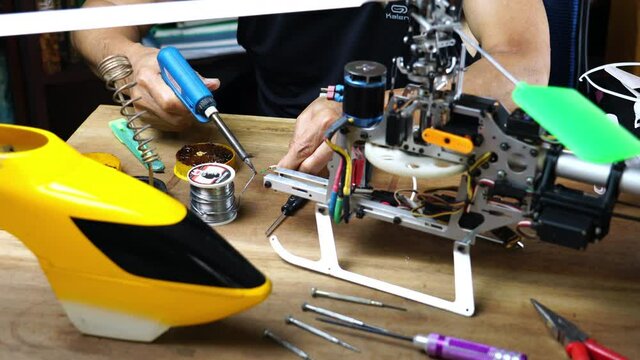 Technician repair radio control helicopter by soldering wire at the radio receiver.