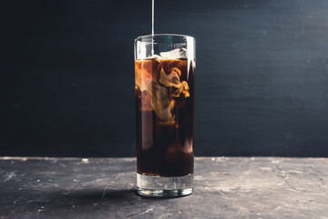 Pouring cream in glass with coffee. Selective focus. 