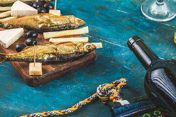 Smoked fish, cheese slices and a wine bottle