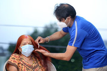 Son in mask and taking care of old and sick mother wearing mask during covid-19. Son combing hair of old mother. Family values. Taking care of elderly. Old Mother and Son.