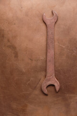 Copper wrench isolated on a copper surface. Aircraft tool. Copy space. Monochrome image. Minimalism. Vertical image.
