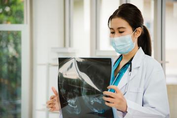 Woman doctor in white labcoat uniform holding x-ray image from human skull to presentation while meeting in conference room at hospital