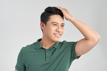 Young handsome man wearing green t-shirt over isolated background Smiling confident touching hair with hand up gesture, posing attractive