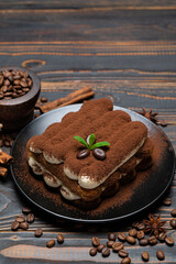 Classic tiramisu dessert on ceramic plate on wooden background