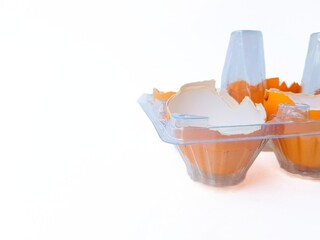 Broken yellow eggs in a plastic transparent tray on a white background.