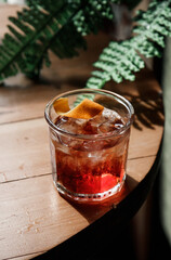cold refreshing Old Fashioned cocktail with orange on a wood on a summer sunny day