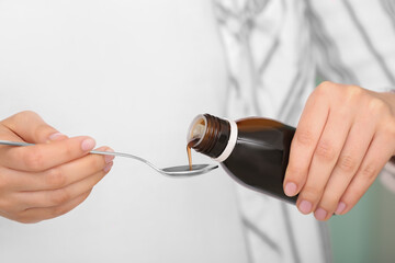 Woman pouring cough syrup from bottle, closeup