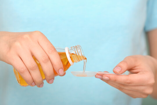Woman pouring cough syrup from bottle, closeup