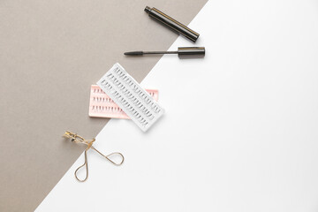 Mascara, eyelash extensions and curler on white and grey background