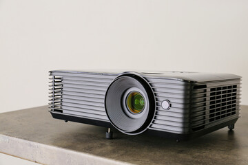Modern video projector on table against grey background