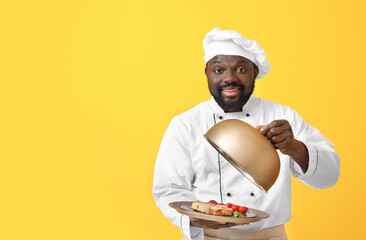 Male African-American chef with tasty dish on color background
