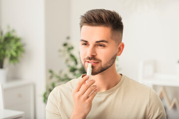 Handsome young man with lip balm at home