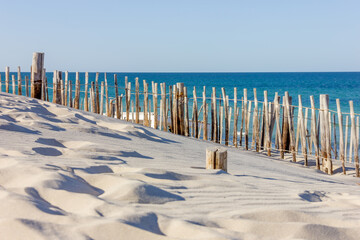 Fence atop sand dunes at beach