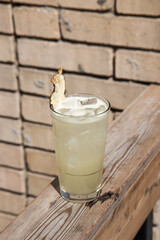 cold refreshing cocktail on a wood on a summer sunny day on the background of a brick light wall with pineapple