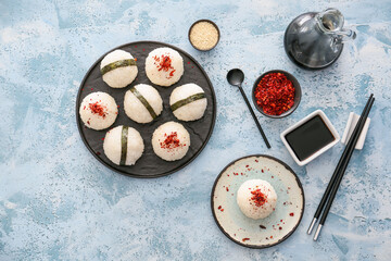 Traditional Japanese onigiri with spices and sauce on color background