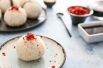 Plate with traditional Japanese onigiri with spices on color background