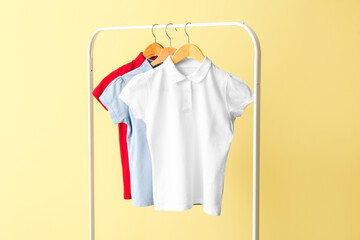 Rack with school uniform on color background