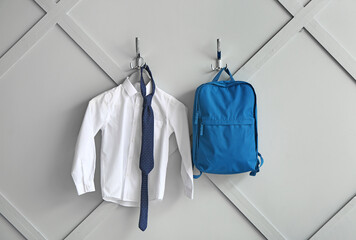 Stylish school uniform with backpack hanging on wall