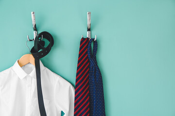 Stylish school uniform hanging on color wall