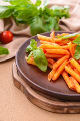 Plate with tasty pasta, basil and tomato sauce on table