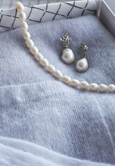 Pearl necklaces and earrings lay on green stones.