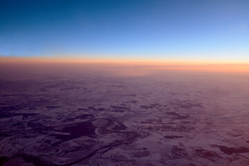 Twilight view on snowy ground from airplane in winter