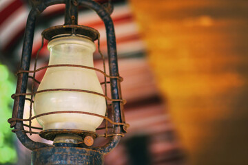 Old weathered iron kerosene lamp closeup hanging on blurry background with copy space