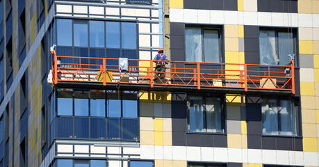 Builder on the wall of a new house in a construction cradle, ulitsa Dybenko 3, Saint Petersburg, Russia June 2020