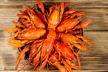 Boiled crayfish in plate on wooden table. Top view