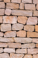 stone wall folded from beige cobblestone uneven vertical pattern