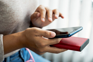 young woman's hand is playing with a smartphone while charging a smartphone battery