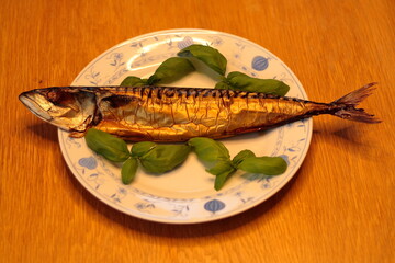 Smoked mackerel, laid on a plate, garnished with green basil