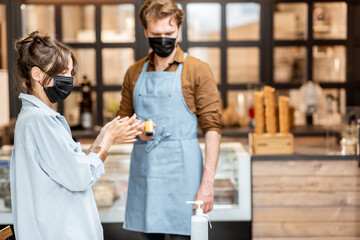 Man checking the temperature of cafe or shop visitors while entering. Concept of a new rules for business during pandemic