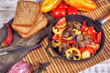 Fried poultry liver with vegetables in a pan . Cooking at home