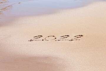 Happy new year 2022 text on the beach. Planning vacation.