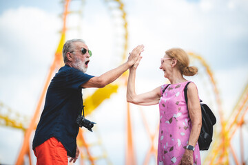 Obraz premium Senior couple enjoying and happy to travel and playing at an amusement theme park, concept of love and happy with old 60's senior people