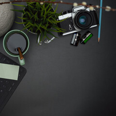 Fototapeta premium Dark modern workspace with coffee mug, wireless keyboard, supplies, decoration and copy space