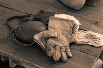 tinted background a pair of leather gloves and a round flask on the table