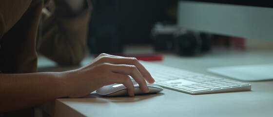 Female worker working with computer device on white office desk with camera and other supplies