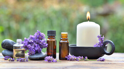 bottles of essential oil among lavender flower arranged on a wooden table in garden with