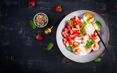 Cottage cheese or curd cheese with strawberries, bananas, walnuts in a blue bowl. Healthy food. Top view, overhead,  copy space