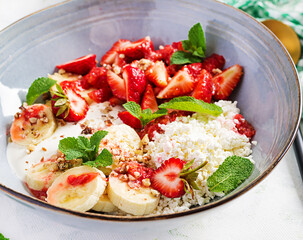 Cottage cheese or curd cheese with strawberries, bananas, walnuts in a blue bowl. Healthy food.