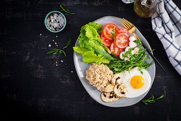 Breakfast oatmeal porridge with fried egg, tomatoes, mozzarella cheese, arugula and fried mushrooms. Healthy food. Top view, overhead,  copy space