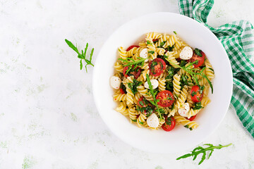 Pasta salad. Fusilli Pasta - Caprese salad with tomato, mozzarella and basil. Top view, flat lay, copy space