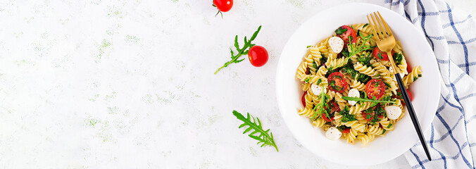 Pasta salad. Fusilli Pasta - Caprese salad with tomato, mozzarella and basil. Top view, banner, copy space