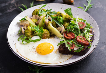 Breakfast with fried egg, broccoli, mushrooms and tomato sandwich. Healthy balanced food.